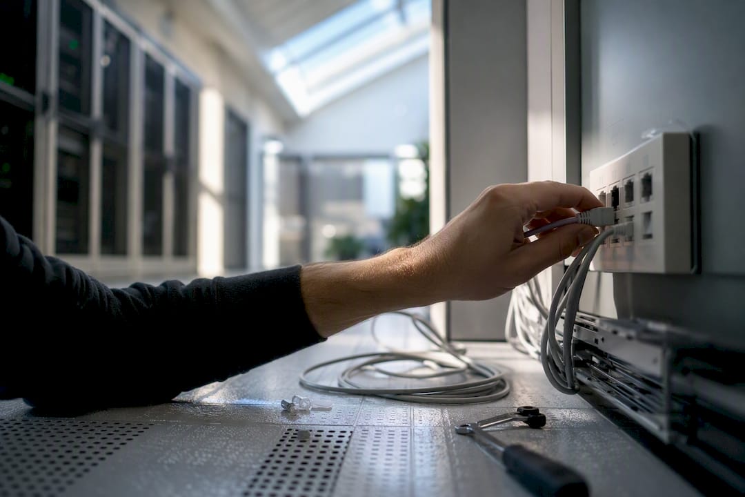 Hand som kopplar in en datakabel i ett serverrum